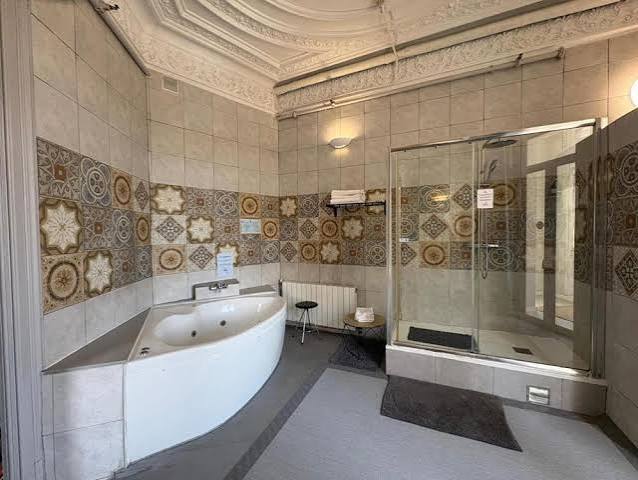 Alt text: Luxurious extra-large private bathroom in a Quadruple Room at Hotel Ginebra Barcelona, with elegant fixtures and city views.